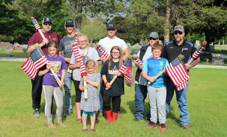 4-H youth and adults hold American flags while posing for picture.