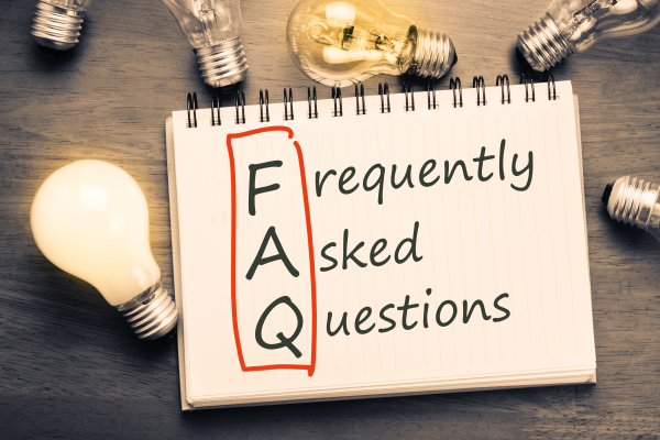 FAQ on notepad with light bulbs in the background