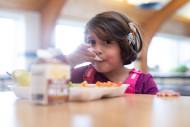 Young girl eats lunch at school cafeteria table