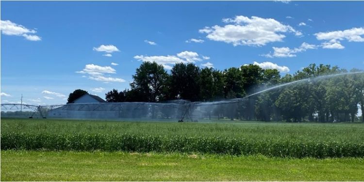 An irrigator spraying water into a field of crops.