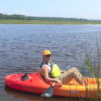 MSU student Kailee Pearson in a kayak sampling wild rice vegetation.