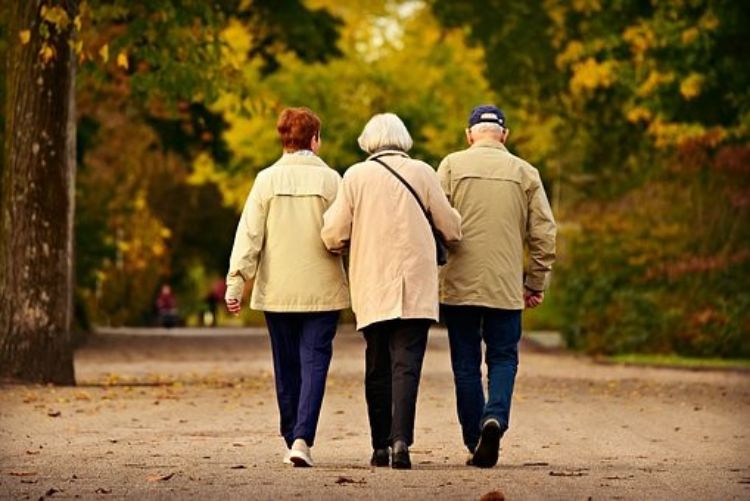 three elderly people walking together during a nice fall day