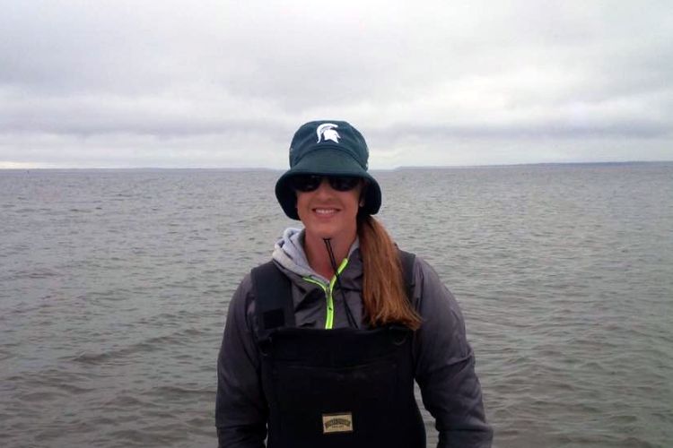 Jennifer Jermalowicz-Jones stands in front of a lake wearing a Spartan bucket hat