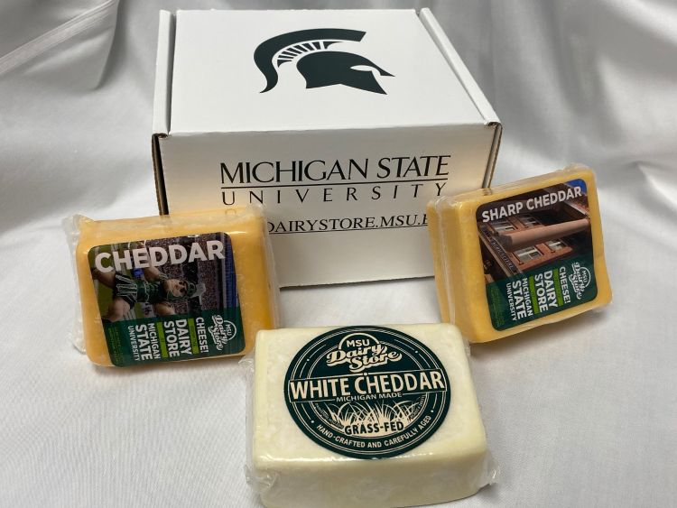 Michigan State University Dairy Store cheese boxes with blocks of cheddar, white cheddar and sharp cheddar cheeses.