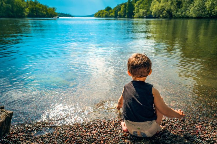 Boy bending down in edge of lake