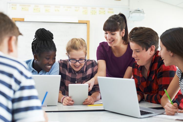 Teenagers with an adult mentor learning with technology.