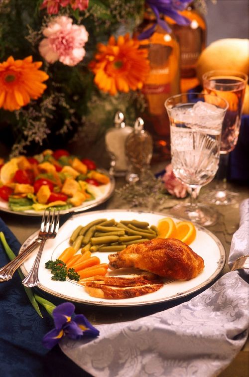 Thanksgiving meal with a plate piled with turkey, green beans, carrots and oranges.
