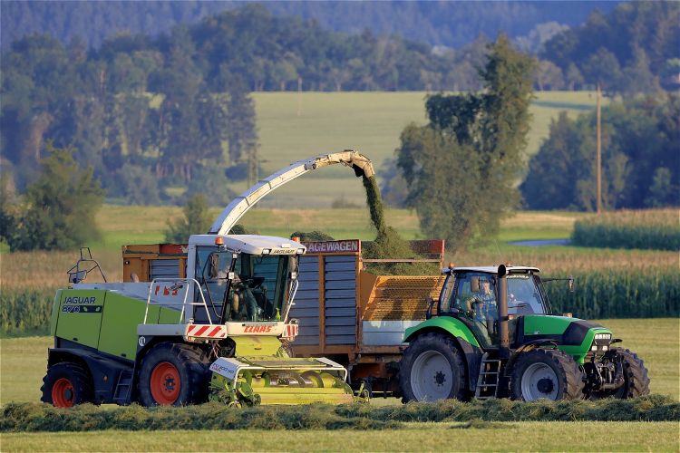 yellow harvester and green tractor in a farm field