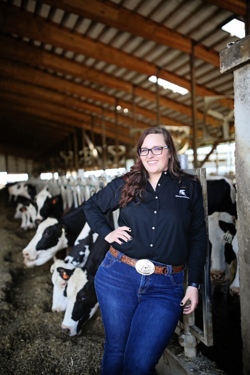Woman standing near a pen of black and white cows