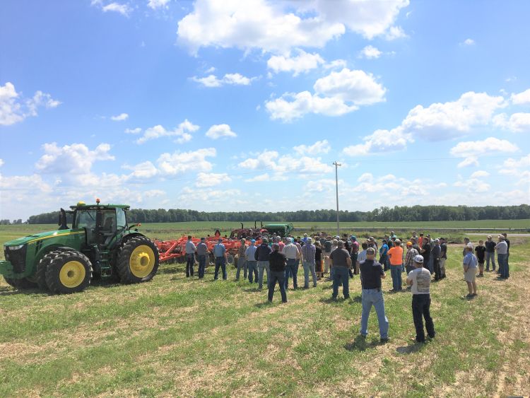 People standing around a tractor observing the land