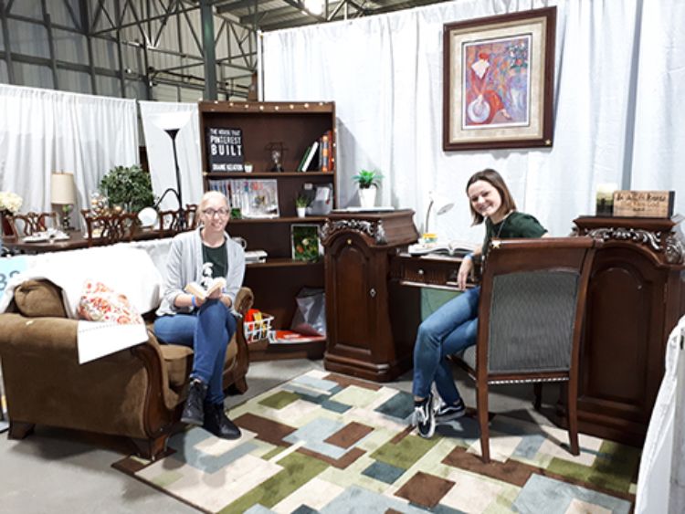 Image of two interior design students sitting in the office they designed for the competition.