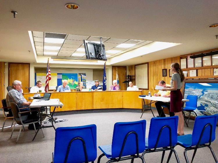 A room full of people listening to a young woman speaking