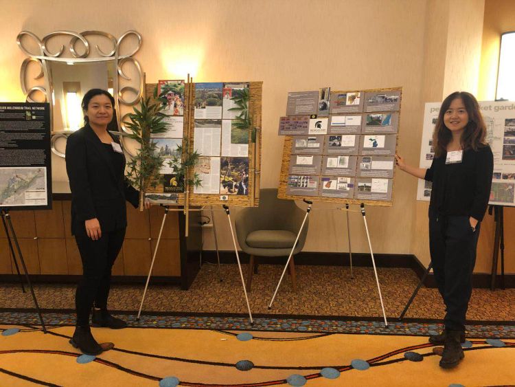 Two women posing next to their research posters.