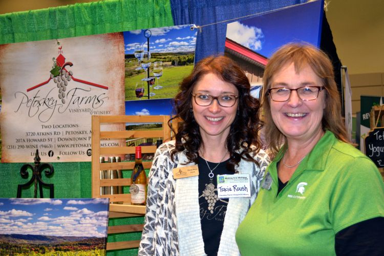 Tracie Roush, owner of Petoskey Farms Vineyard and Winery, and Wendy Wieland, innovation counselor for the MSU Product Center, take a photo outside of Tracie’s booth at the 2019 Making It In Michigan Conference and Marketplace Trade Show. Tracie and her husband Andy received the Start Up to Watch Award at the conference.