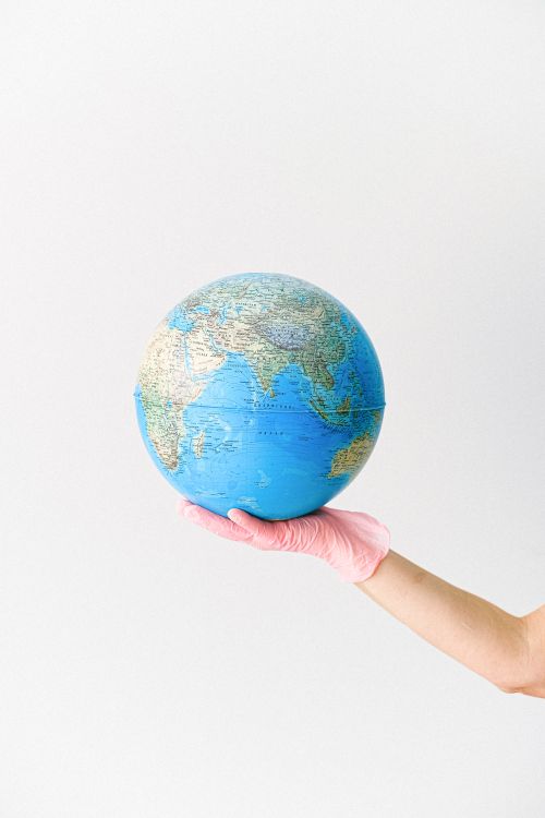 A picture of a globe being held by gloved hand.