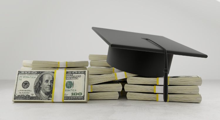 Stacks of bills with a graduation cap on top.