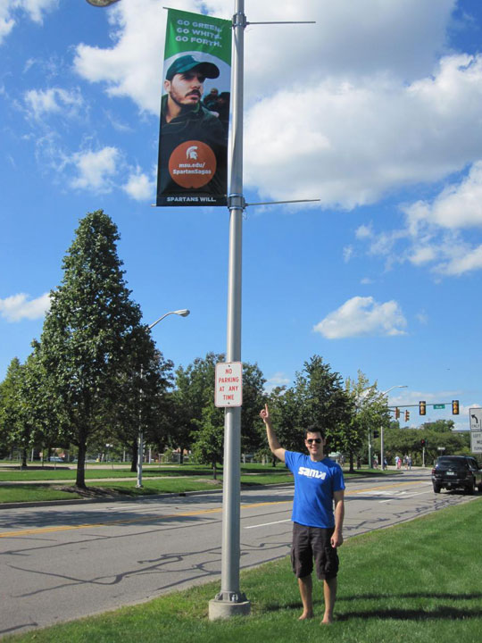 Neil Carter in front of his banner on the MSU campus