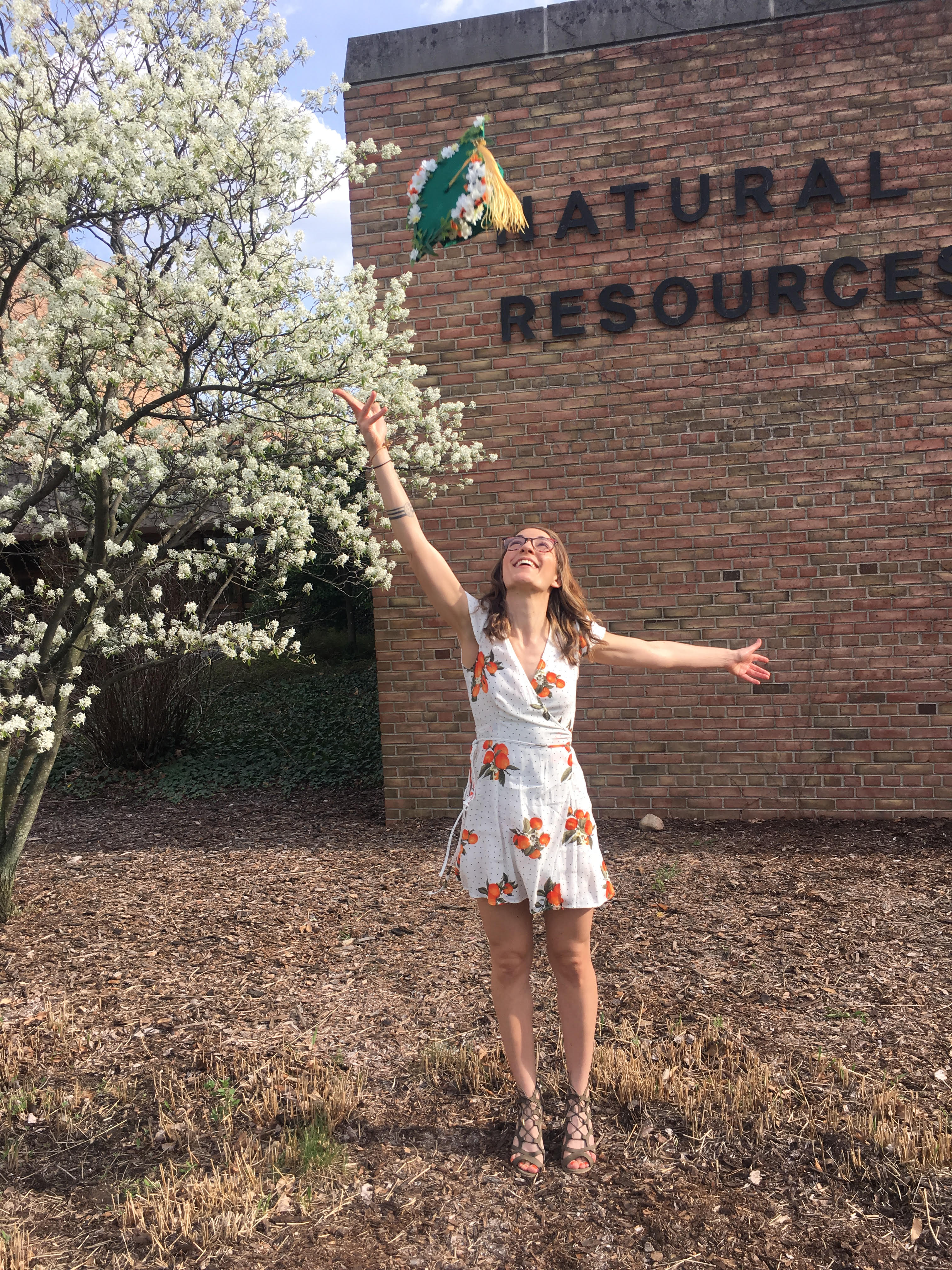 Kate tosses her cap at graduation in front of the MSU Natural Resources Building.