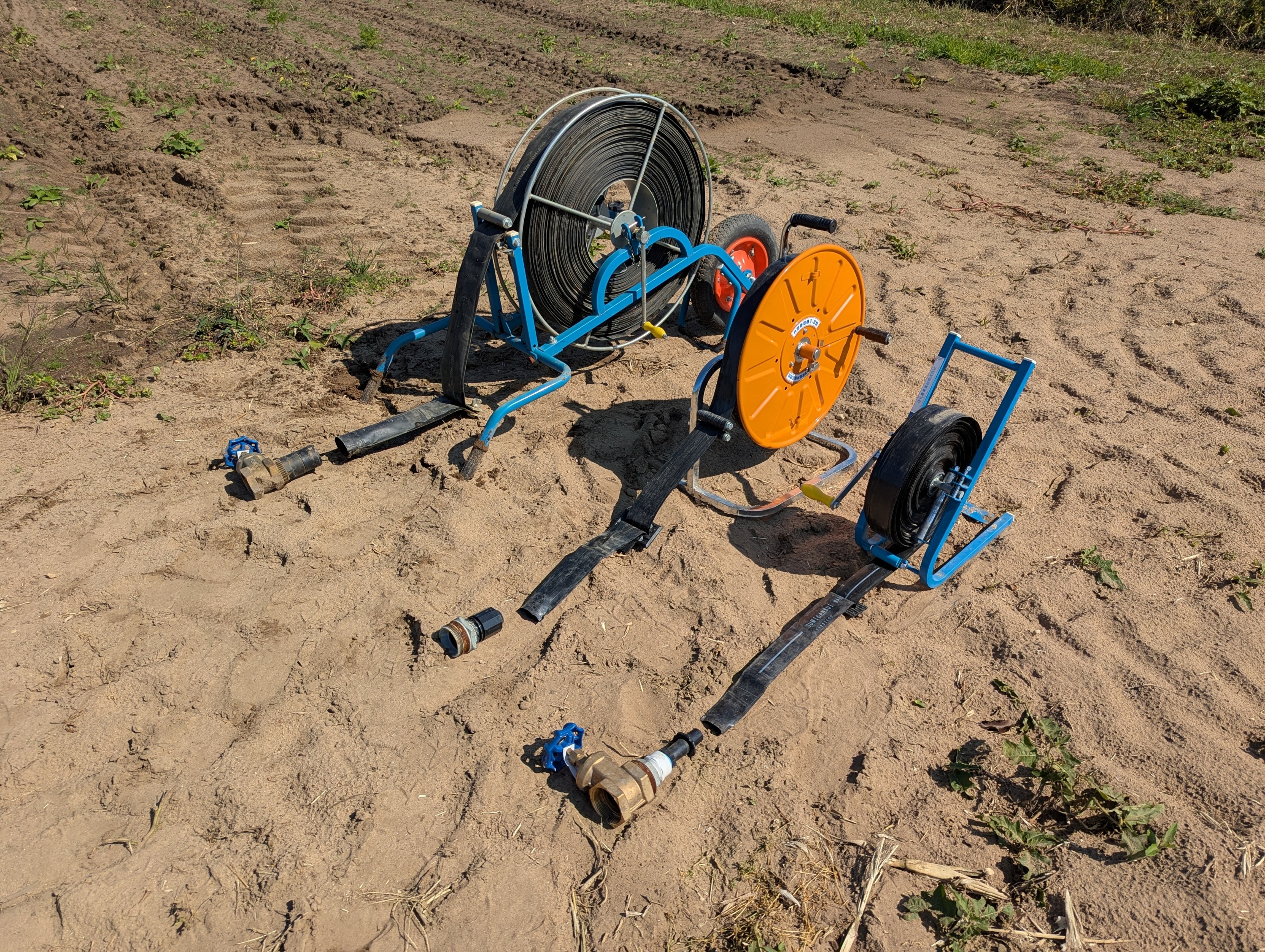 The tubes, winders and connectors of the SumiRain, R-Wide and Mark-II sitting on a sandy ground.