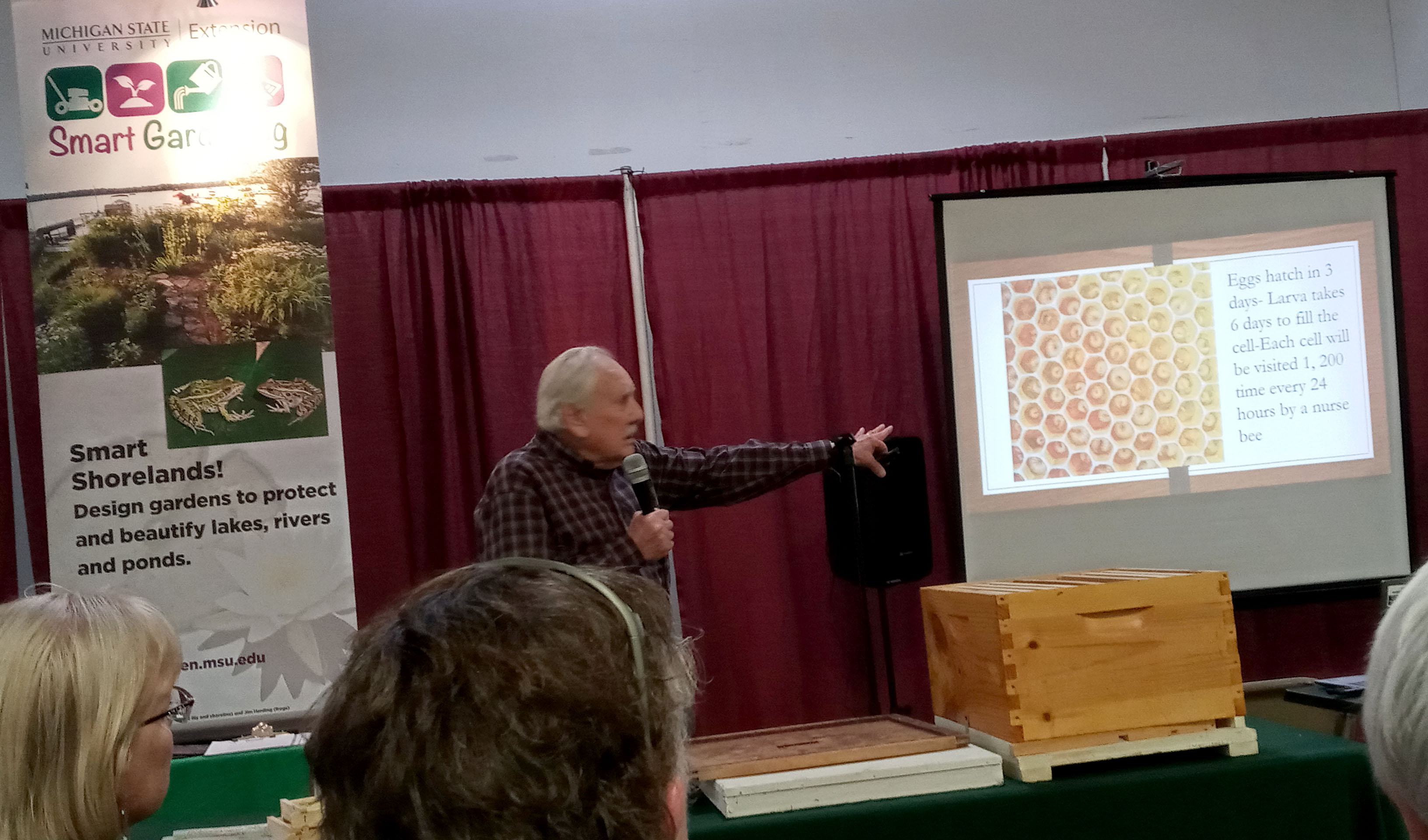 A man gives a presentation to a crowd on honey bees.
