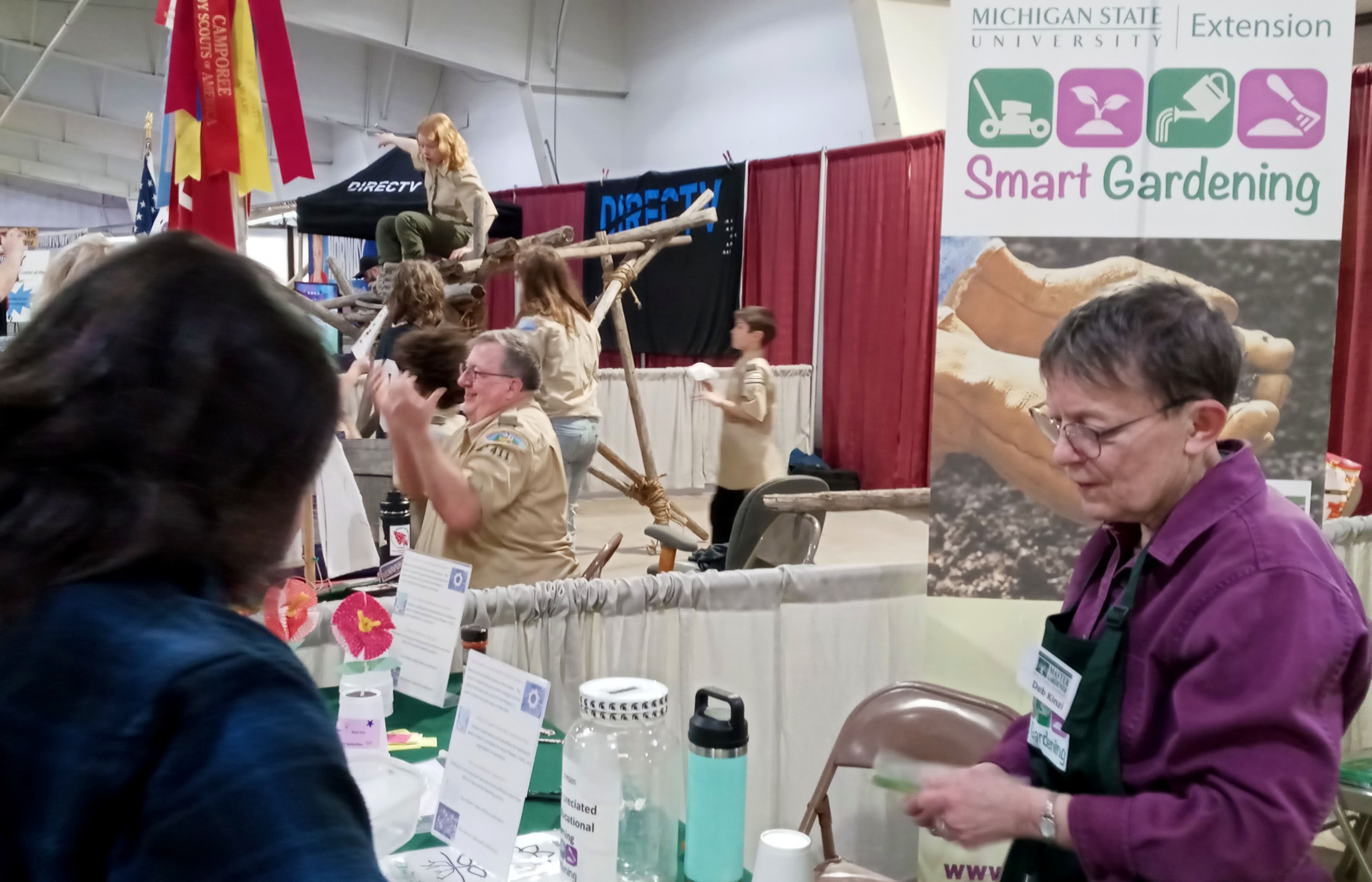 Two women stand at a booth talking.