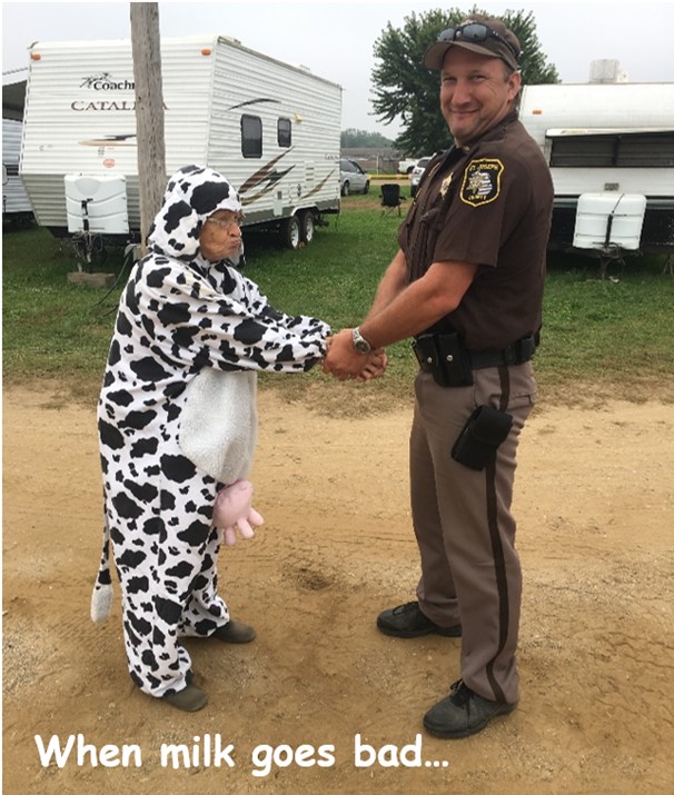 A cop holding the wrists of a woman dressed as a cow