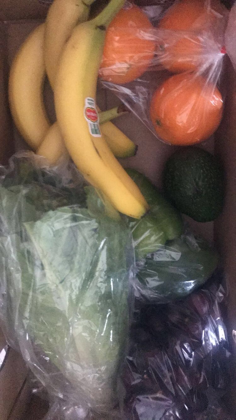 Produce box with bananas, oranges, lettuce, limes.