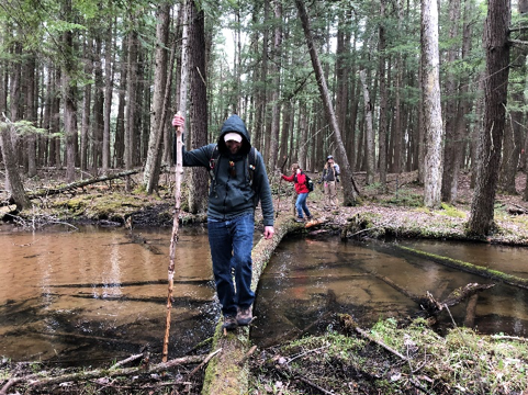 Lee Spangler crossing a river on a fallen tree