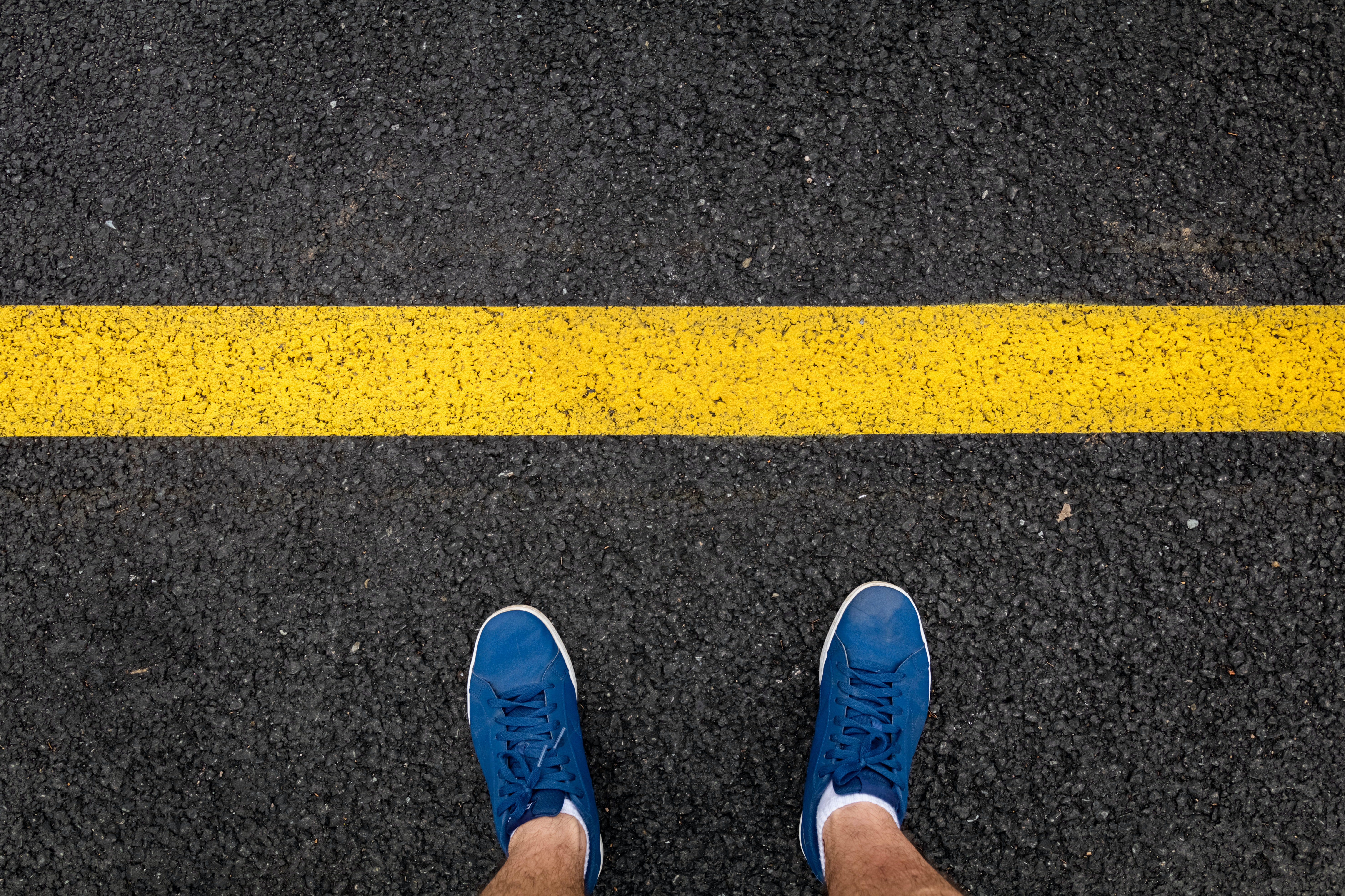 Picture of two feet next to a yellow line.