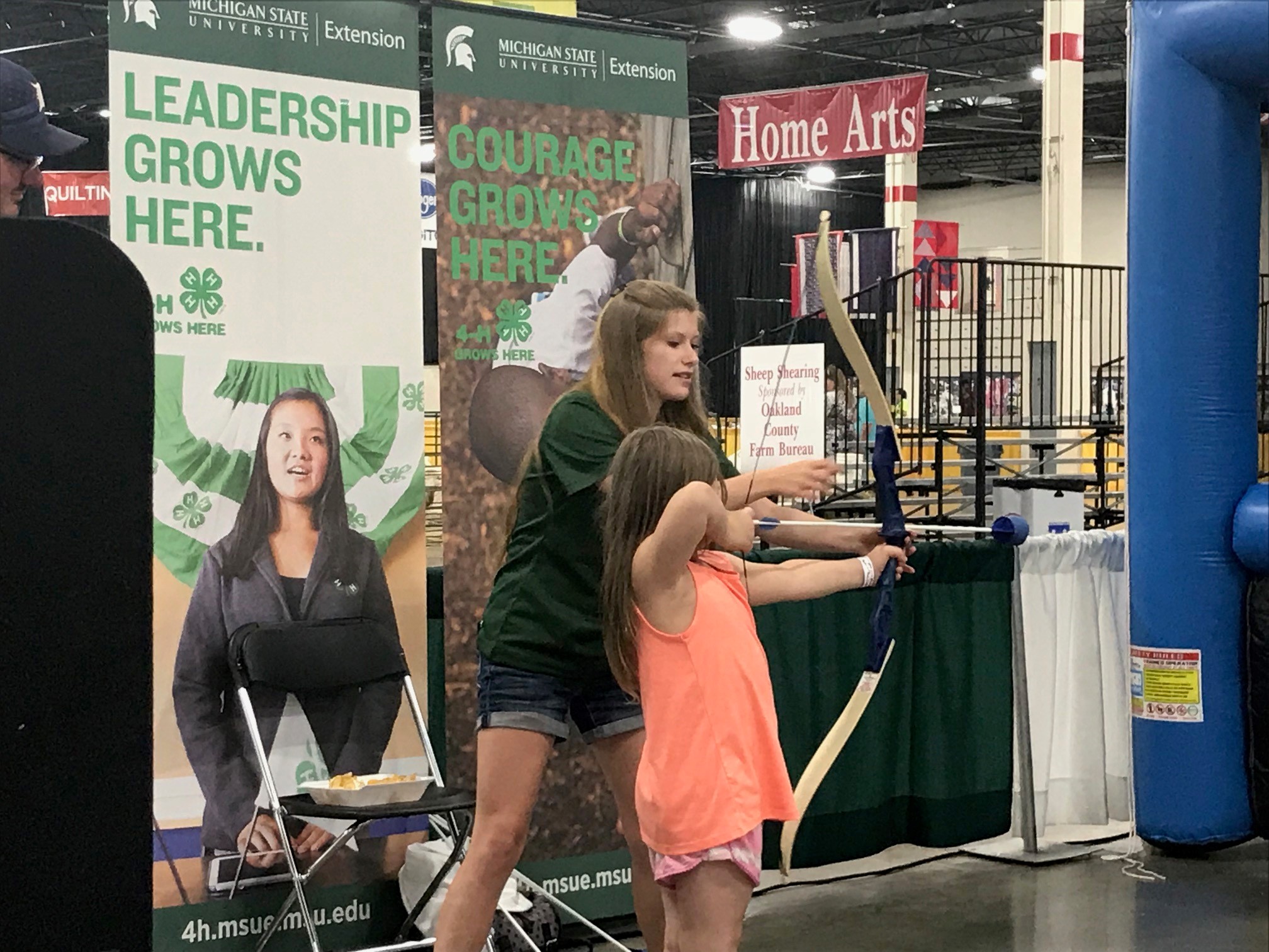 A Michigan 4-H State Youth Leadership Council member putting their ambassador skills to work helping at a booth at the Michigan State Fair.