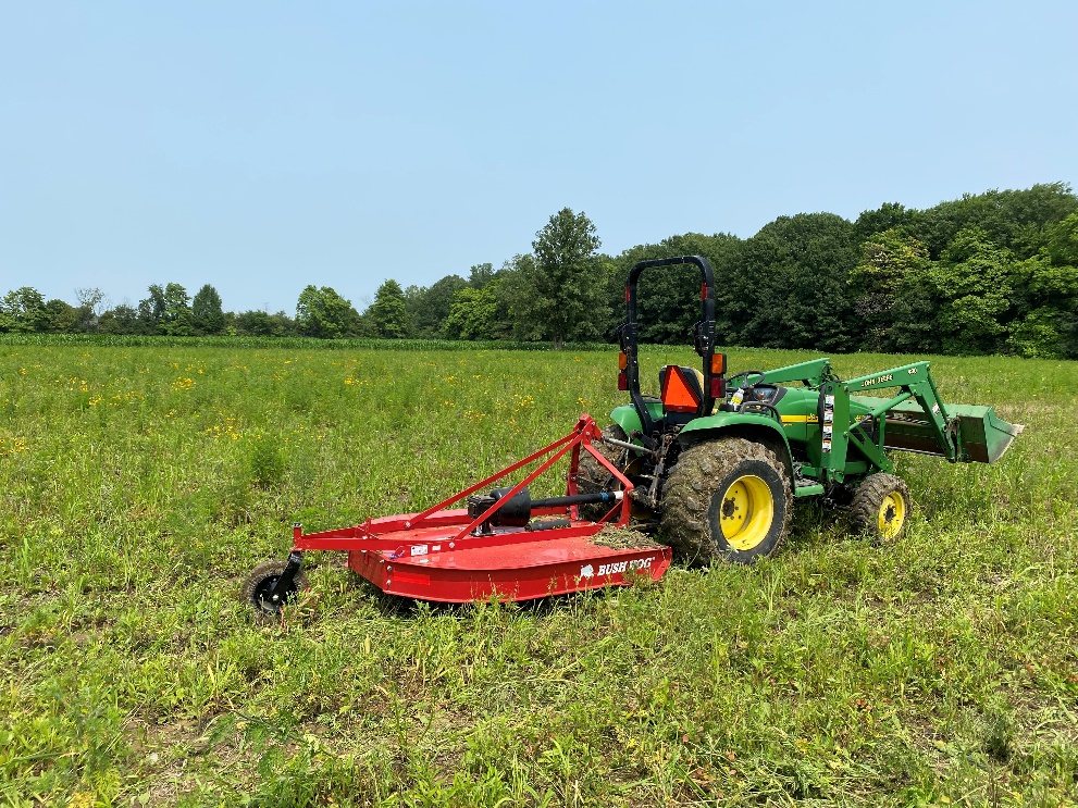 photo of a tractor and attachment in a field of grass and flowers