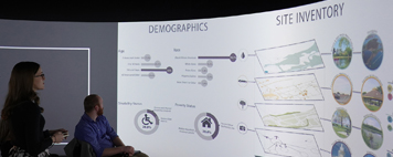 Landscape architecture student presenting their project during the LA Senior Show. Using VR technology, the student's project is presented on a screen that runs around the perimiter of the round room.