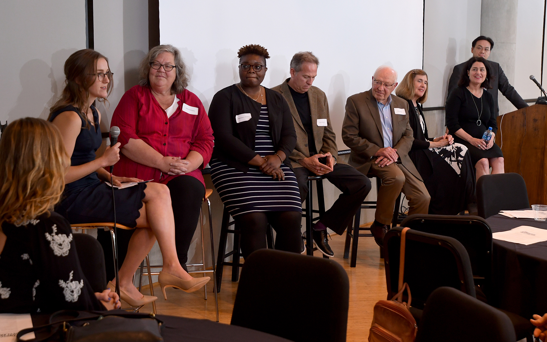 Panelists sitting on stools during landscape architecture event.