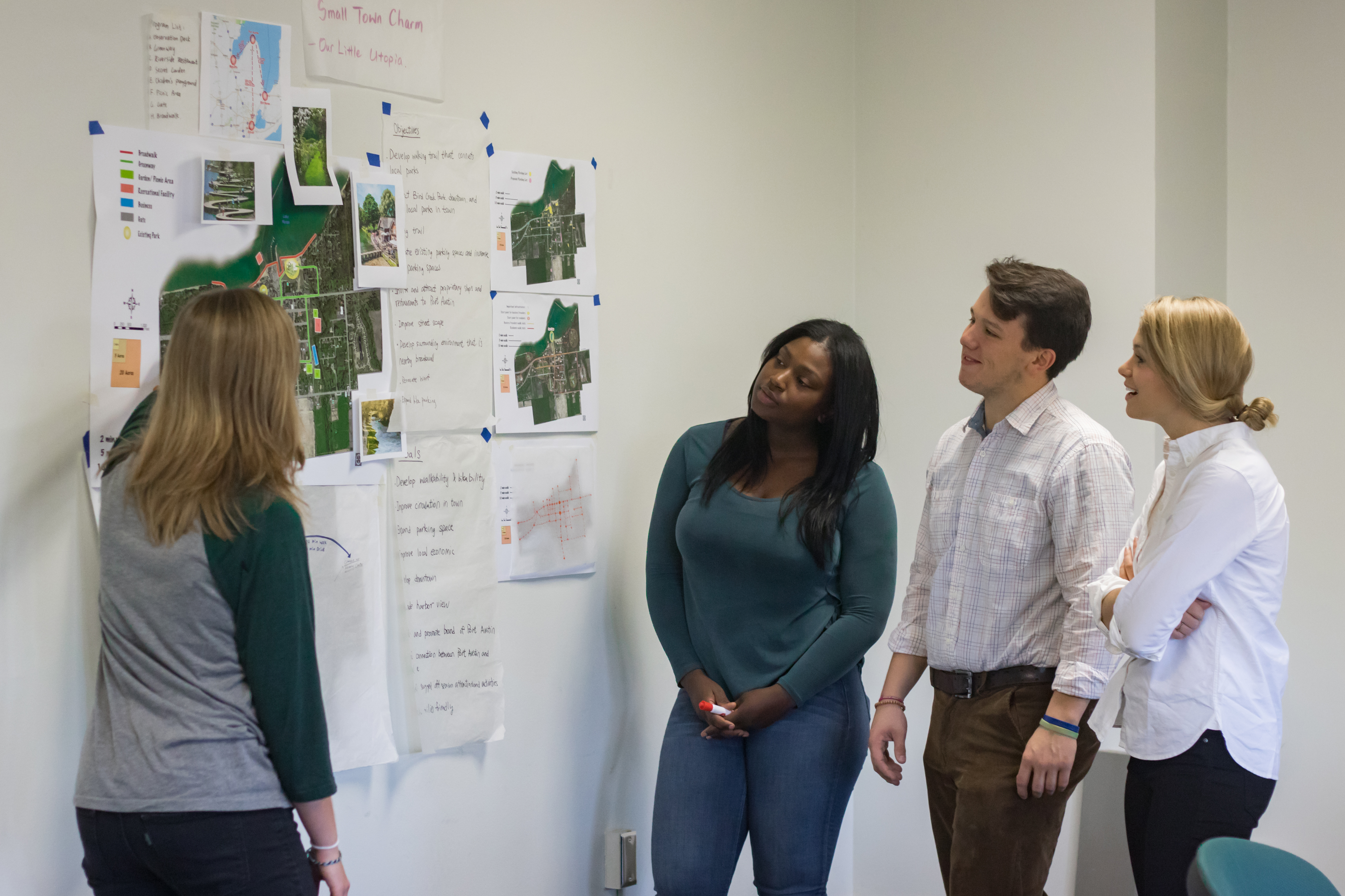 Urban and Regional Planning student presenting a poster while others watch.