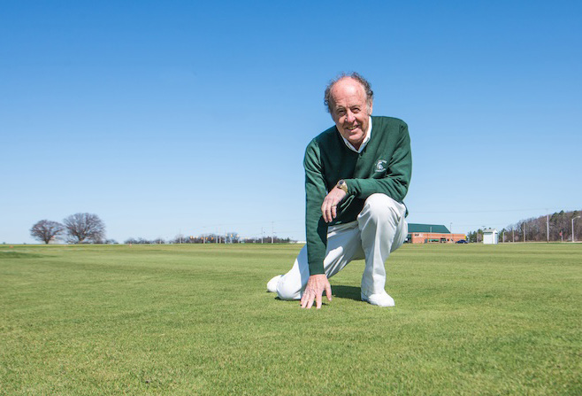 Dr. Joe Vargas kneeling on turfgrass.