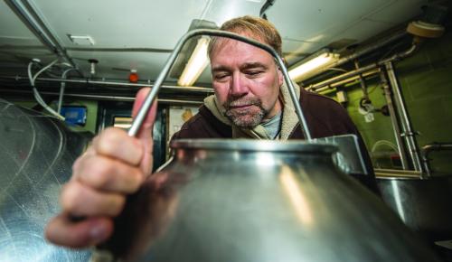 Ronald Erskine, MSU professor of large animal clinical sciences, inspects a milk pail on the MSU dairy farm. His research has found that by improving animal health through more effective farm employee training, the need for antibiotics, and therefore development of resistance, is reduced.