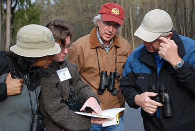 Birdwatchers look at a bird ID guide