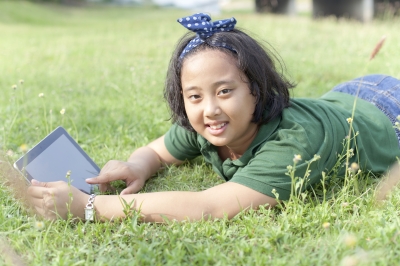 girl laying in grass on tablet