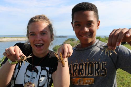 Students smiling while holding crayfish.