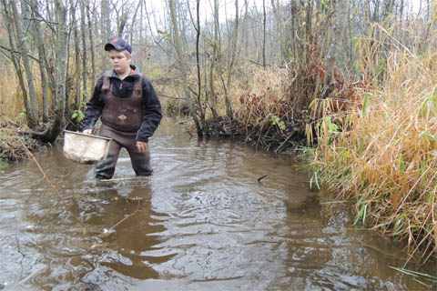 Male student wading in the river.