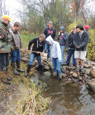 Group of students collecting samples from river.