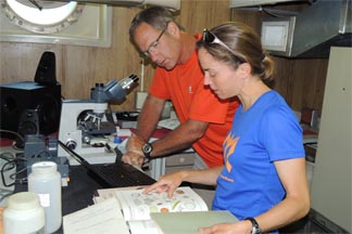Teachers conduction research with microscope on R/V Lake Guardian.