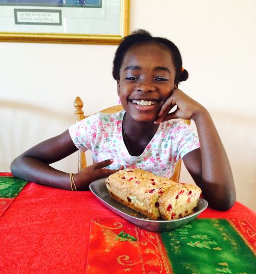 Child posing with a loaf of cranberry bread.