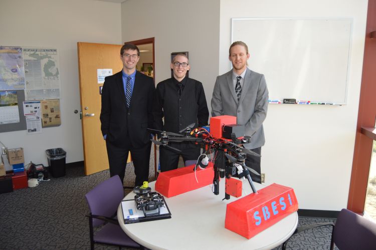 Saginaw Valley State University students Carson Beauchaine, Chris Rush, and Justin Krenzke stand with the water sampling UAV they built. Their adviser on the project Professor Thomas Kullgren is not pictured. Photo credit: David Karpovich